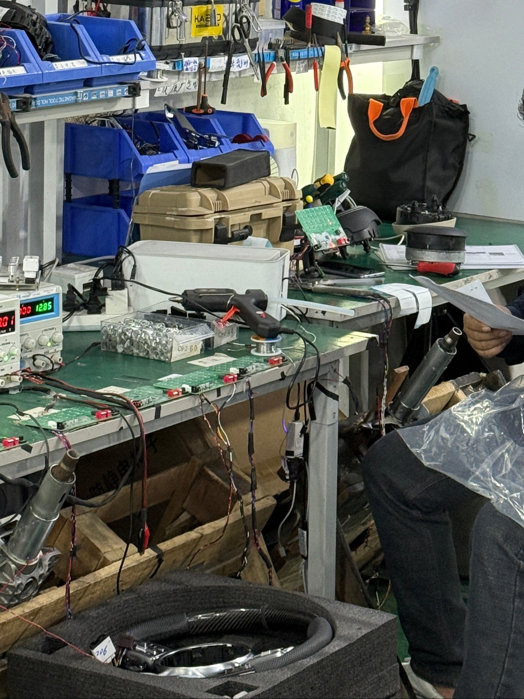 Two people working on a vehicle in a garage setting with tools and equipment.